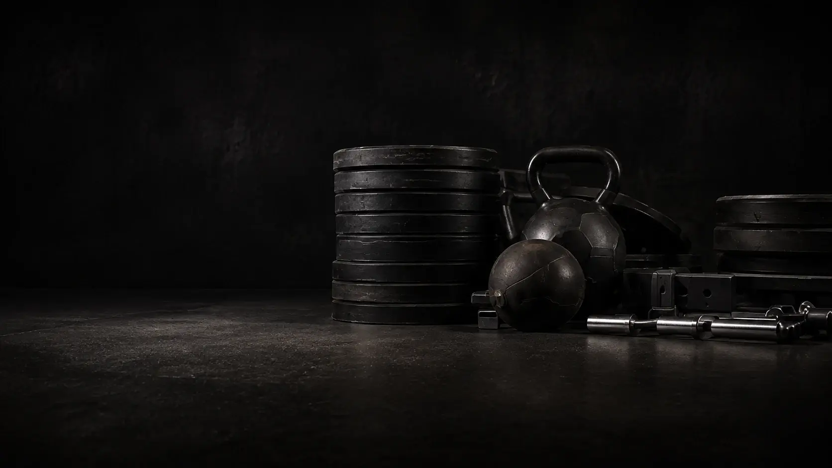 Disques de fonte, kettlebell et medicine ball posés au sol dans la salle